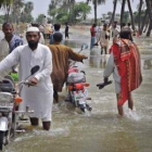 Los desplazados avanzan a través del agua para buscar un refugio ante las inundaciones.