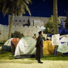 Un judío ultraortodoxo camina mirando «la ciudad campamento» en Jerusalén.