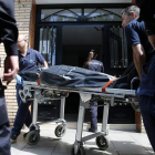 Operarios sacan un cadáver del edificio.