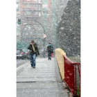 Un joven caminando ayer bajo la nieve primaveral por Valladolid