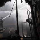 Un bombero trabaja en el interior de la fábrica afectada, desde lo alto de un depósito.