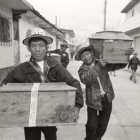 Dos campesinos caminan con los féretros de sus hijos.