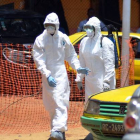 Dos miembros de la Cruz Roja se dirigen a retirar los cadáveres de dos fallecidos por ébola, el lunes en Conakry.