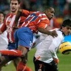 El delantero valencianista Villa intenta llevarse un balón ante el rojiblanco Perea