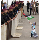 Un niño con una bandera palestina y un cartel de Abás se acerca a unos policías.