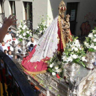 Una mujer saluda desde su balcón a la Virgen de La Encina, portada por vecinos de Sancedo, Ocero y Cueto en la calle del Paraisín.