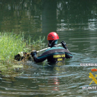 Un agente de la Guardia Civil busca en el río al desaparecido.