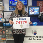 La vendedora de La Bañeza posa orgullosa con una copia del décimo premiado.