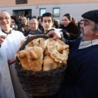 El párroco y los fieles, durante la bendición de los panes ayer en la parroquia cacabelense.