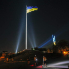 Una bandera y el monumento a la Patria, iluminado con los colores de Ucrania, en Kiev. SERGEY DOLZHENKO