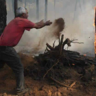 Uno de los vecinos de Tabuyo suelta tierra con rabia contra las llamas para tratar de apagarlas.