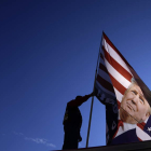 Un americano arría una bandera con la efigie de Donald Trump. WILL OLIVER
