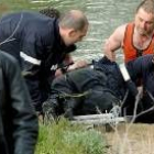 Los bomberos en el momento de rescatar del río el cuerpo sin vida de un anciano