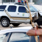 Un policía apunta con su arma a un indígena armado con un arco y flechas frente al Congreso de Brasilia.
