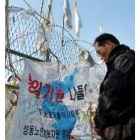 Un norcoreano en la frontera, repleta de pancartas que piden la unificación