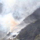 Dos helicópteros echando agua en la ladera de la montaña afectada por el incendio, ayer a media tarde, en Chano. L. DE LA MATA