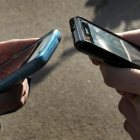 Una foto de archivo con dos personas escribiendo en sus teléfonos móviles.
