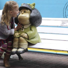 Una niña con una escultura de Mafalda en Buenos Aires.