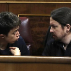 Los máximos dirigentes de Podemos, Iñigo Errejón y Pablo Iglesias, discuten en sus escaños del Congreso.