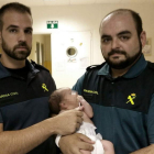 Los dos agentes de la Guardia Civil junto al bebé rescatado.