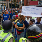 Un grupo de personas protesta frente a miembros de la Policía Nacional Bolivariana (PNB) en la ciudad de Caracas (Venezuela).