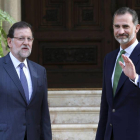 El rey Felipe VI saluda junto al presidente del Gobierno, Mariano Rajoy (i), hoy al Palacio de Marivent, en Palma de Mallorca, donde se han reunido en el único despacho que ambos celebran este verano en la residencia de verano de la familia real.