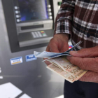 Un hombre saca dinero de un cajero automático. KATIA CHRISTODOULOU