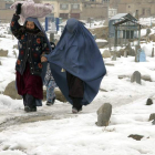 Dos mujeres afganas caminan por el cementerio nevado en Kabul.