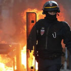 Un policía antidisturbios camina cerca del fuego de una barricada en Toulouse.