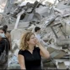 Mujeres libanesas cubren sus rostros al pasar frente a casas dañadas
