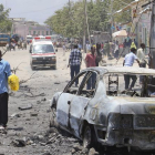 Varias personan observan el lugar de la explosión de un coche bomba frente al Ministerio de Educación en Mogadiscio (Somalia),
