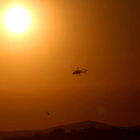 Un sol abrasador con un helicópetero que combate un fuego en el Mediterráneo. ORESTIS PANAGIOTOU