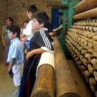 Varios niños se apoyan en una de las antiguas máquinas textiles que expone el Batán museo