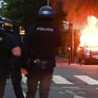 Varios policías ante un coche ardiendo, en Nantes.