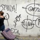 Una mujer pasa por delante de las pintadas en la sede del PP