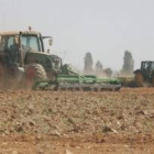 Dos máquinas agrícolas realizan trabajos en una zona de cultivos de regadío en la provincia leonesa