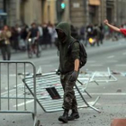 Un joven forma una barricada con vallas durante la manifestación en Barcelona.