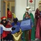 Tres niños recogen sus regalos en la sede de Cruz Roja, desde donde partió la comitiva real