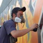 Uno de los graffiteros acabando su dibujo del muro del campo de fútbol de San Andrés