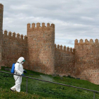 Un trabajador desinfecta un pasamanos de la muralla de Ávila por el coronavirus. RAÚL SANCHIDRÁN