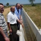 José Valín, tercero por la izquierda, observa una acequia que inauguró en un nuevo regadío de León