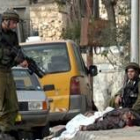 Dos soldados israelíes contemplan el cadáver de uno de los palestinos