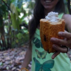 Una mujer muestra el fruto del cacao.