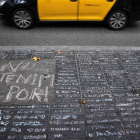 Un taxi pasa junto a los mensajes de apoyo escritos con tiza en una acera de Las Ramblas de Barcelona.