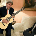 Kerry con la guitarra española que le ha regalado Margallo, sentado en el sofá, esta tarde en el Palacio de Viana, en Madrid.