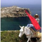 Un marroquí sobre un burro con la bandera pasa por delante del islote