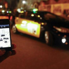 Un usuario consulta la aplicación de Uber junto a la Sagrada Família, en diciembre del 2014.