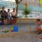 Dos niños juegan con la arena del parque infantil ante la mirada de sus familiares