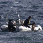 Un operario del equipo de salvamento recupera del mar uno de los cuerpos sin vida