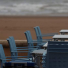 Sillas y mesas en la playa de la Malvarrosa de Valencia, donde un turista practica deporte. KAI FÖRSTERLING
